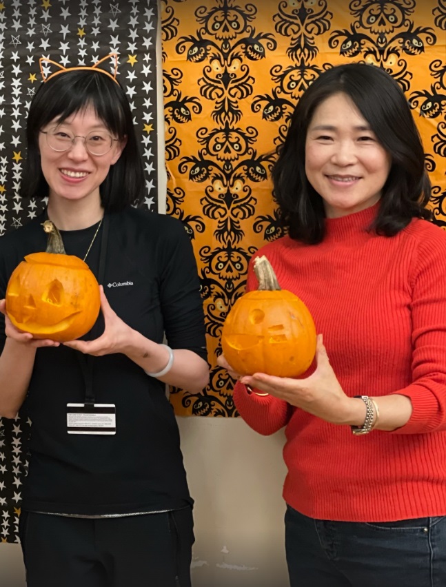 Two people hold up carved jack'o'lanterns