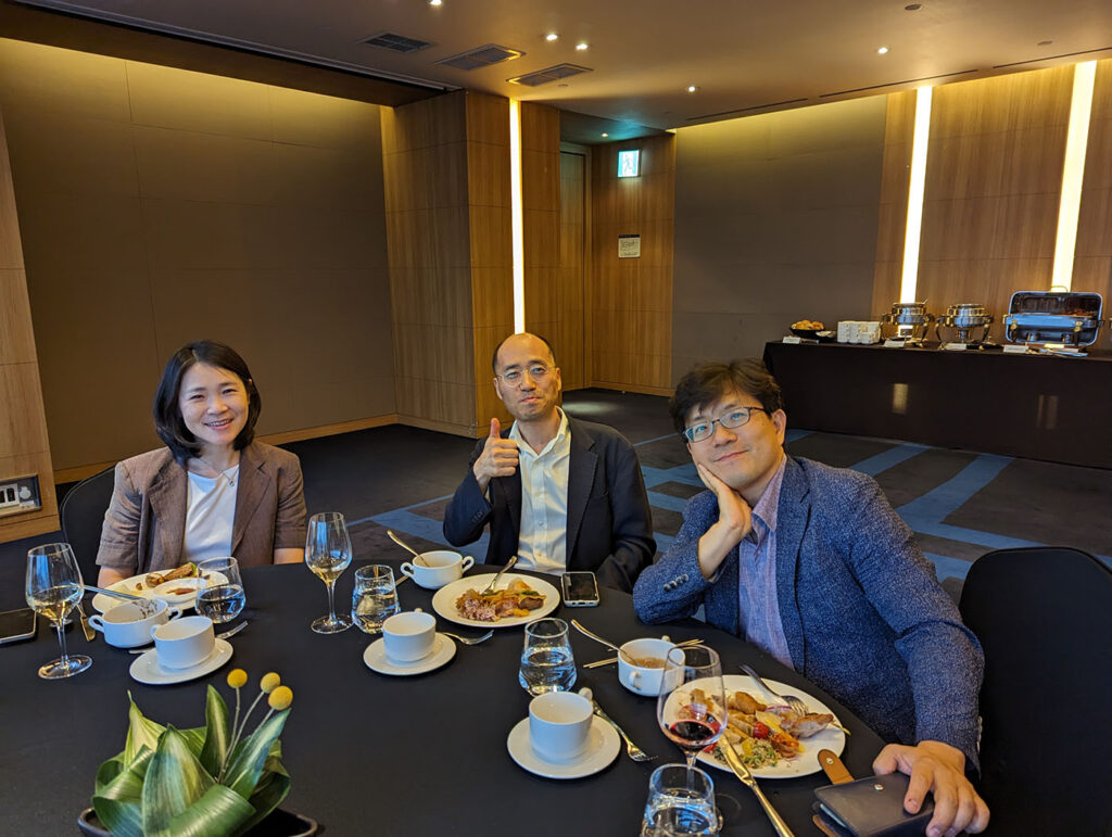 Three people sit at a dinner table in a hotel event room